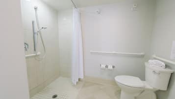 Un baño con ducha, inodoro y barras de apoyo.