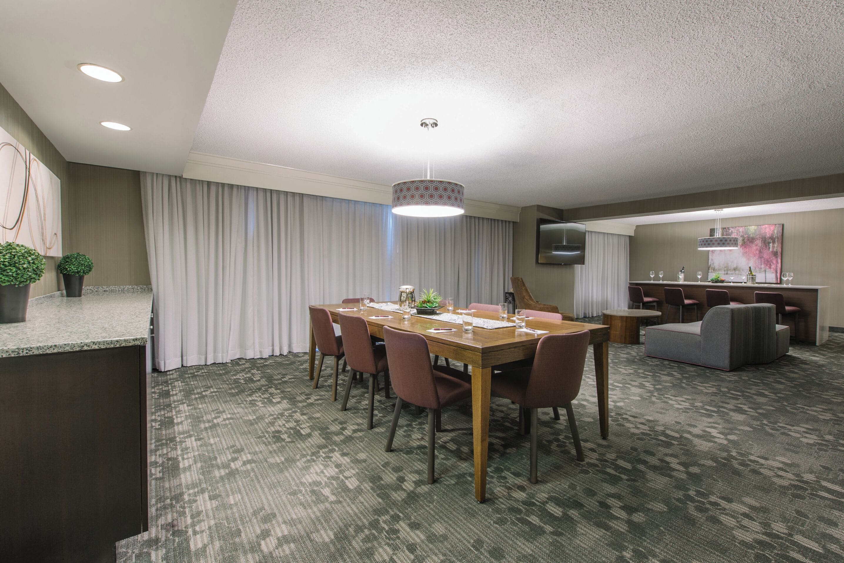 A conference room with a long table, chairs, a small side table, and a decorative lamp.