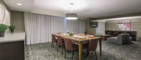 A conference room with a long table, chairs, a small side table, and a decorative lamp.