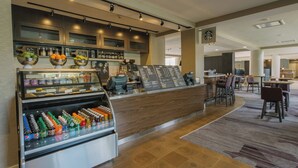 A modern hotel lobby with a coffee bar, seating area, and a display case with snacks. - Courtyard by Marriott Nashua (Nashua)