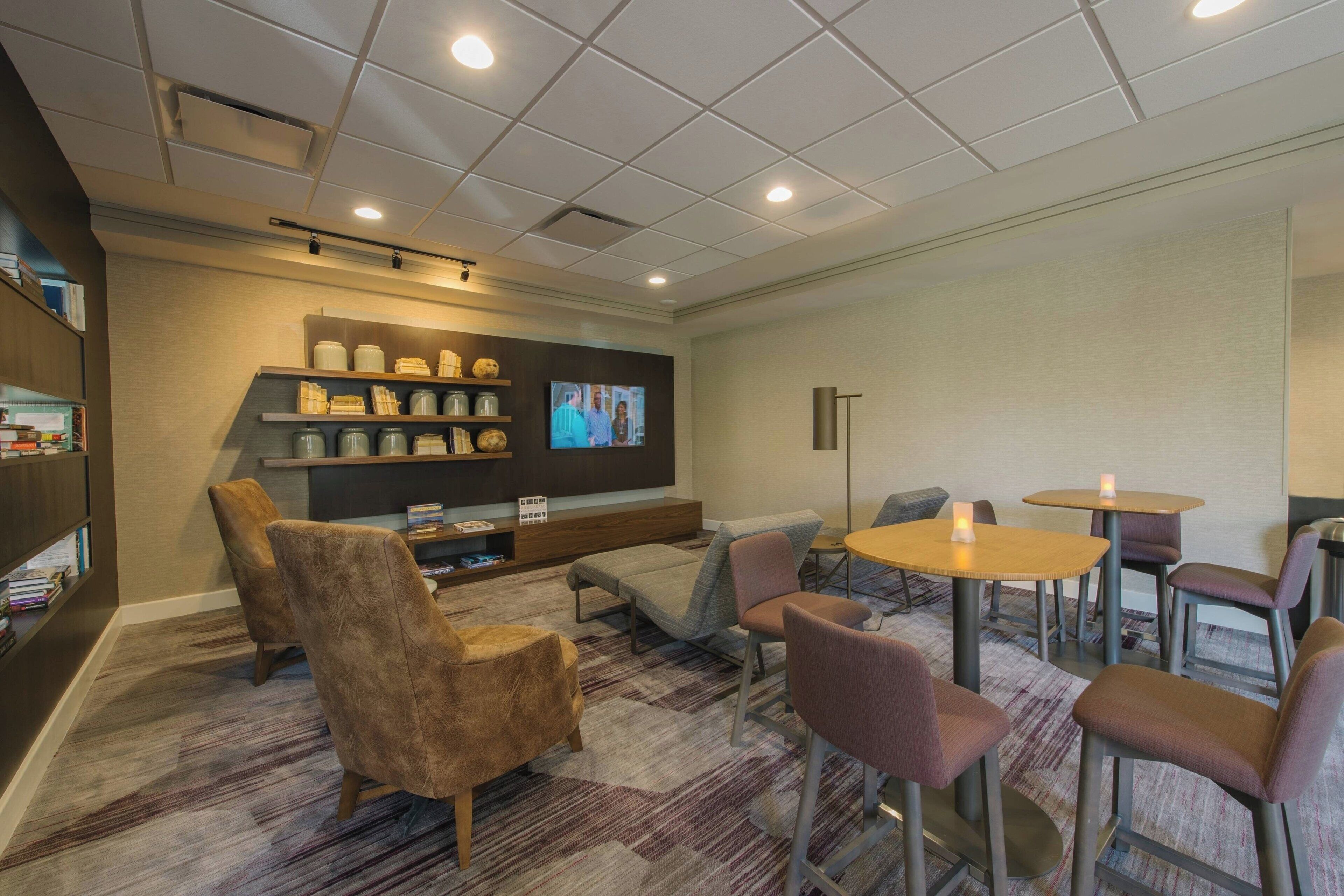 A cozy lounge area with seating, a television, and a bookshelf.