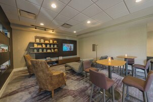Un espacio de descanso acogedor con asientos, televisión y una estantería.