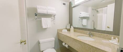 A bathroom with two sinks, a toilet, a towel rack with towels, and a mirror.