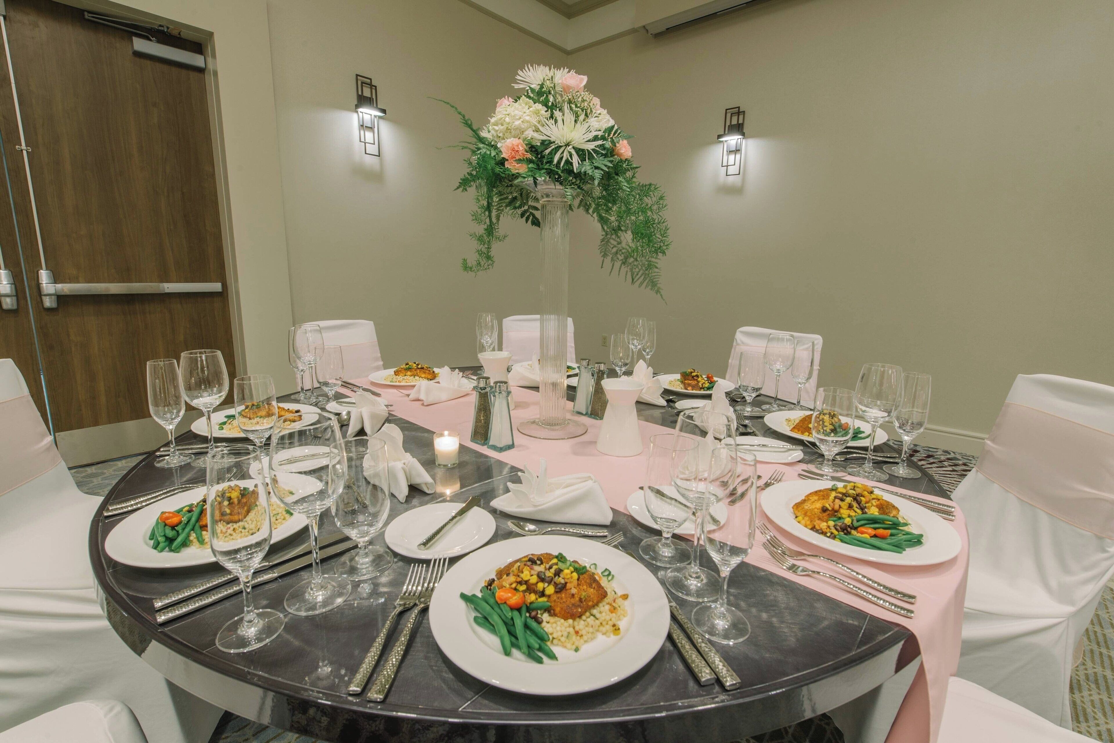 A round dining table set for a meal with plates of food, wine glasses, and cutlery.