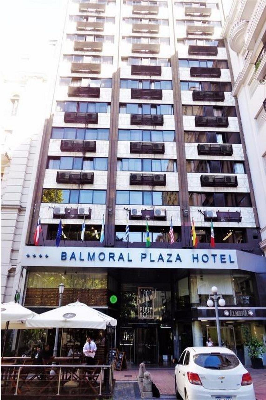 A multi-story hotel with balconies and a sign reading 'Balmoral Plaza Hotel'.