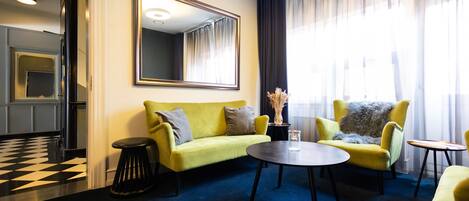 A modern hotel room with a yellow sofa, a round coffee table, and a large mirror.