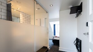 A modern hotel room with a glass partition, a black and white patterned floor, a bed, and a mounted TV. - Milling Hotel Ritz (Aarhus)