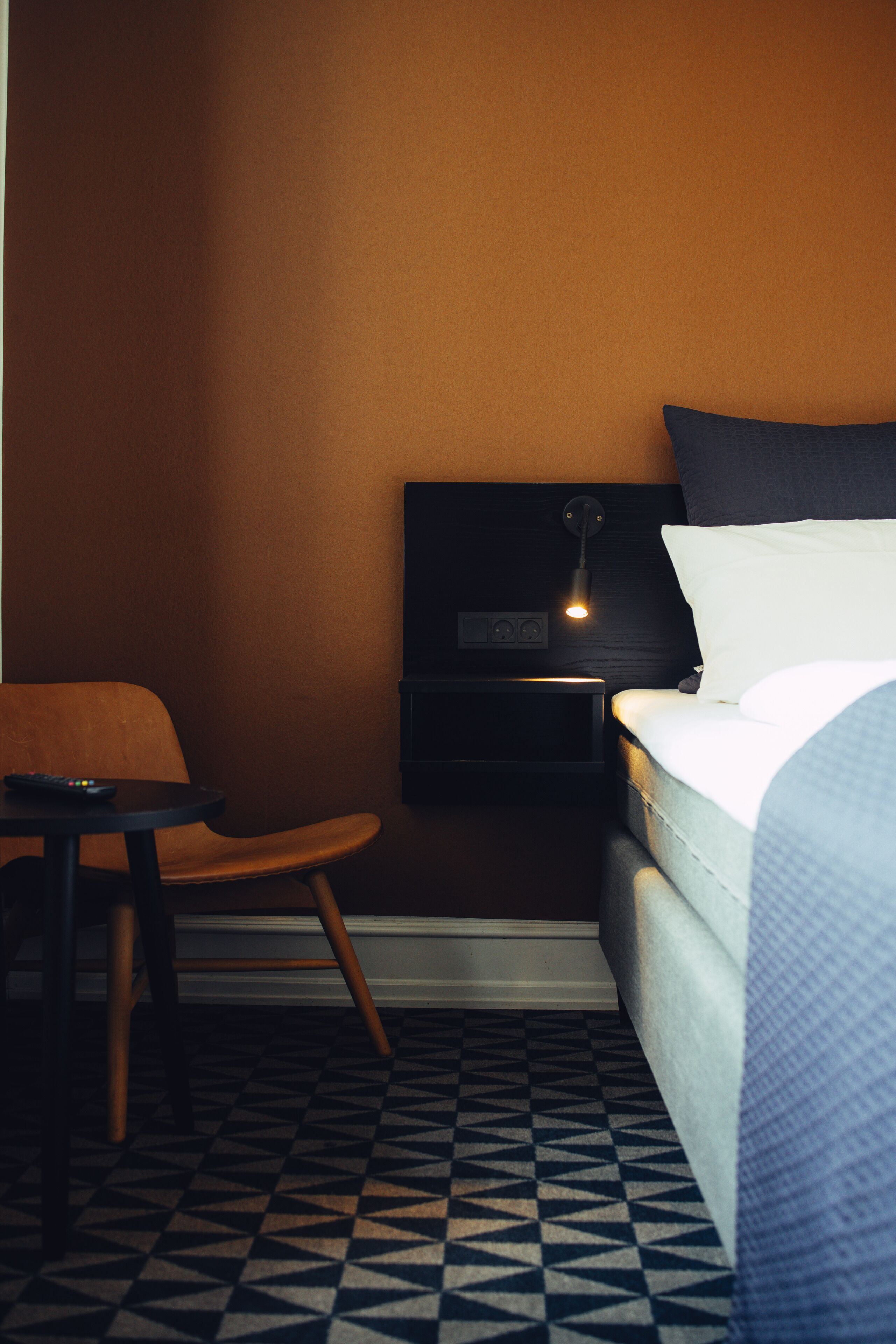 Une chambre d’hôtel avec un lit, une table de chevet, une chaise et une petite table.