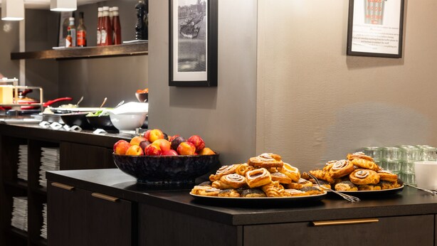 A buffet area with a bowl of fruit and a plate of pastries. - Milling Hotel Ritz (Aarhus)
