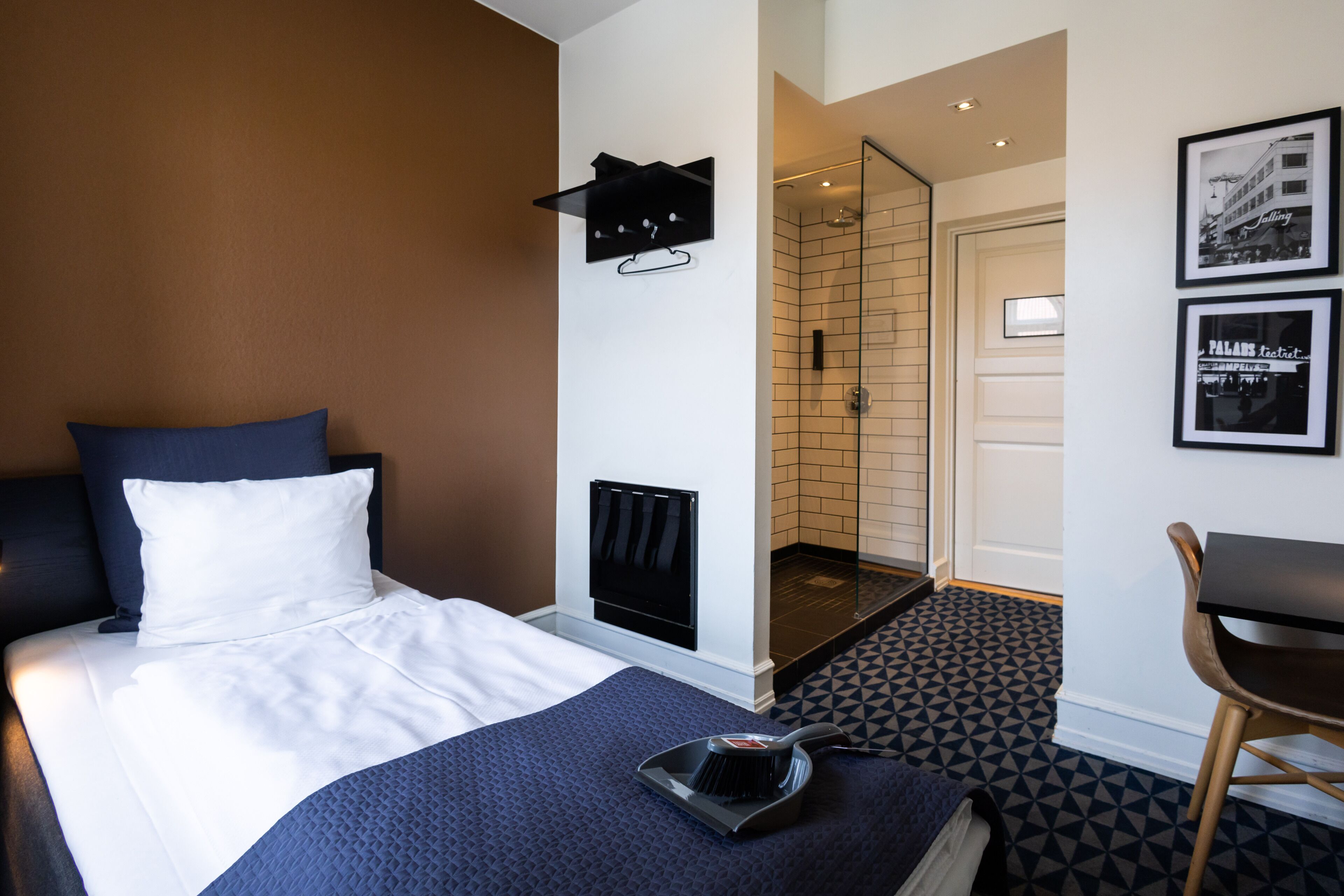 A hotel room with a bed, a shower, a desk, and a chair.