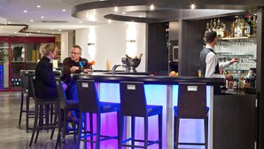 Zona de bar moderna con una barra curva, taburetes y un cantinero.