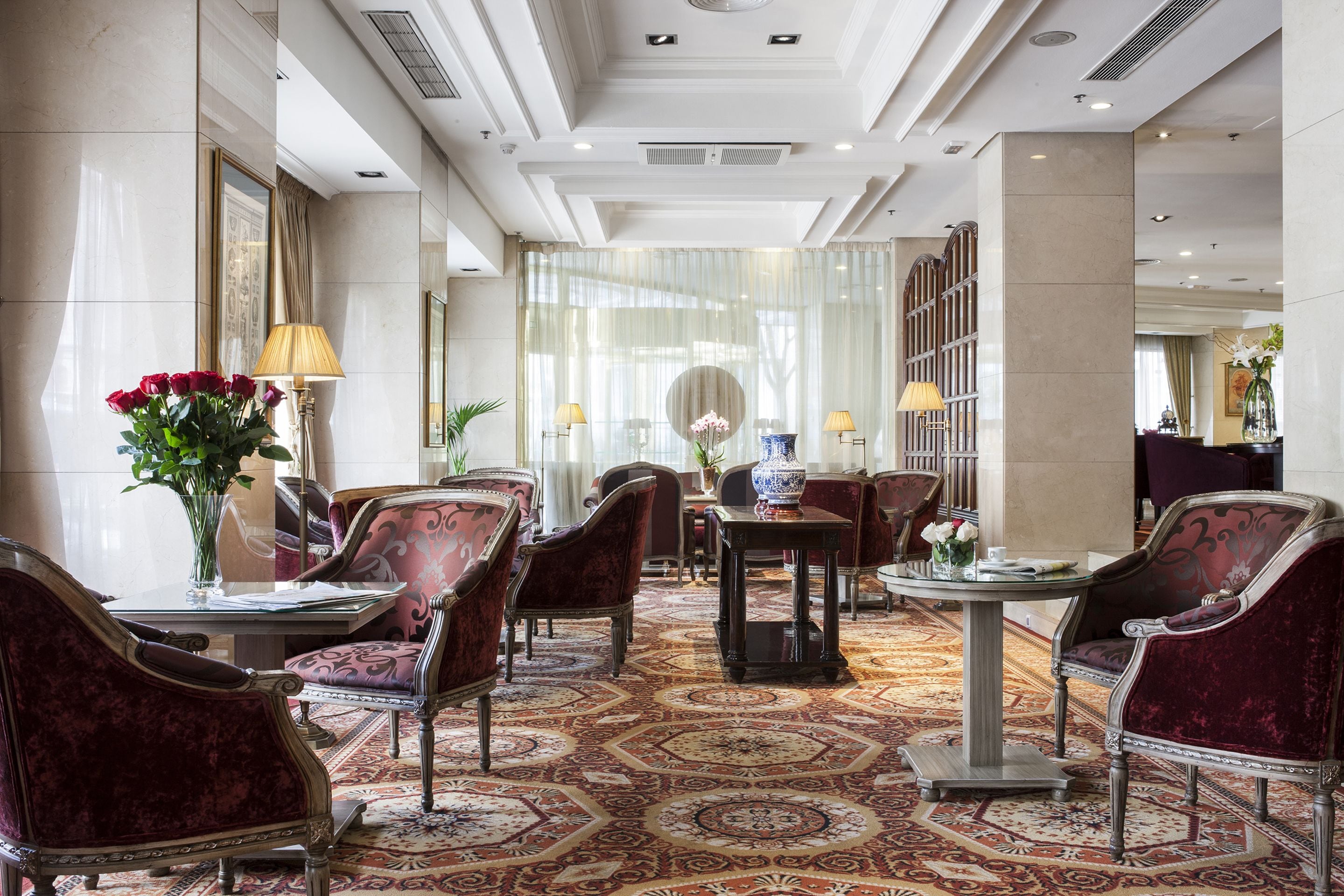 Eine Hotelhalle mit aufwendigen Möbeln, einem gemusterten Teppich und einem großen Spiegel.