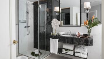 A modern bathroom with a glass-enclosed shower, a marble sink, and a vanity with towels and toiletries.