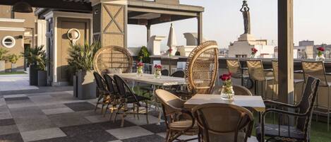 An outdoor patio with checkered flooring, wicker furniture, and a statue.