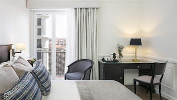 Habitación de hotel con cama, escritorio, silla y vista a la ciudad a través de la ventana.