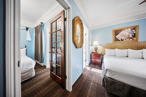 A hotel room with a large bed, a smaller bed, a wooden door, a mirror, and a painting on the wall. - Fitzgerald Hotel (San Francisco)