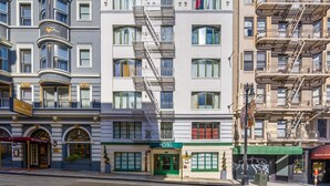A hotel with a green entrance, multiple windows, and a fire escape. - Fitzgerald Hotel (San Francisco)