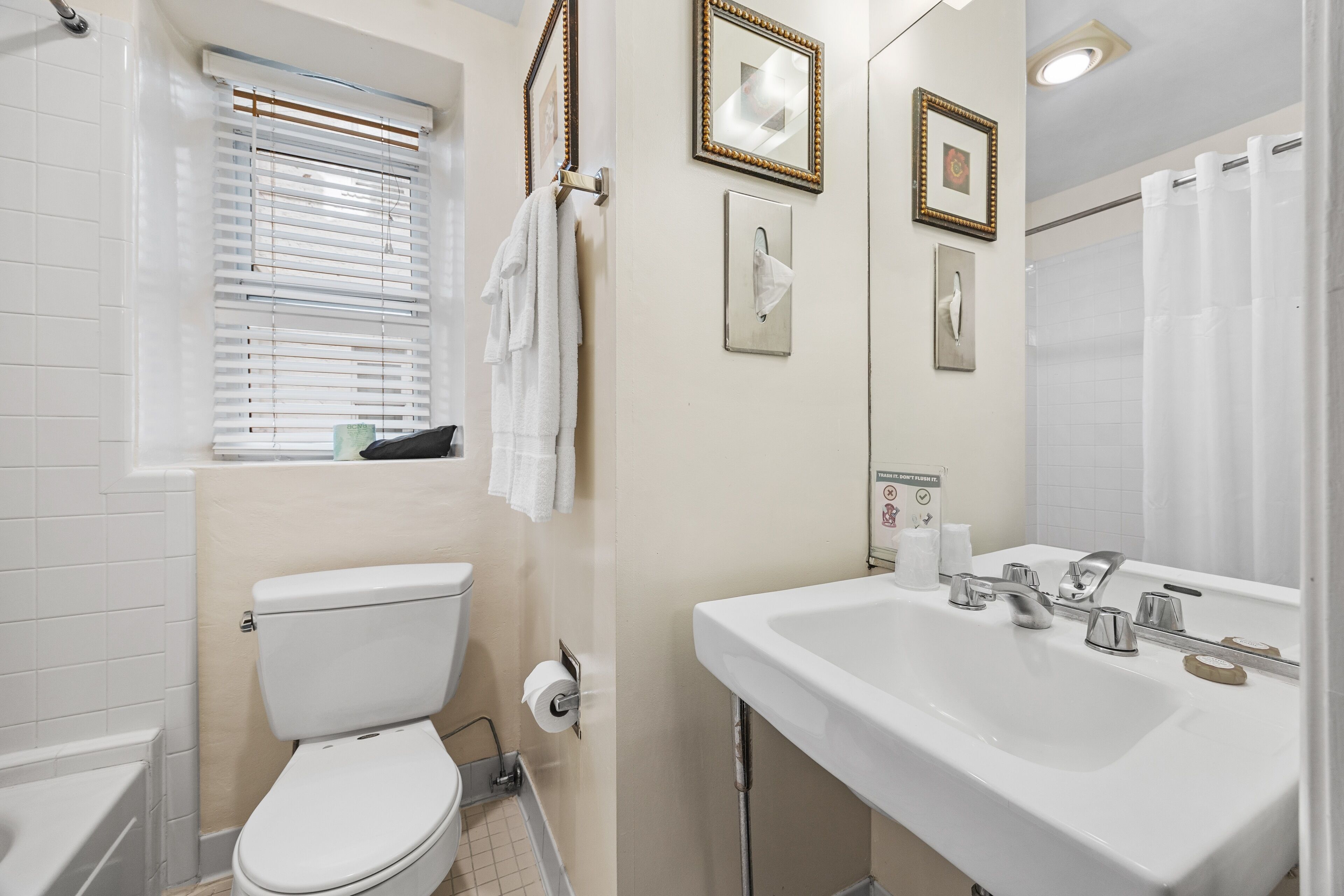 A bathroom with a toilet, sink, and window with blinds.