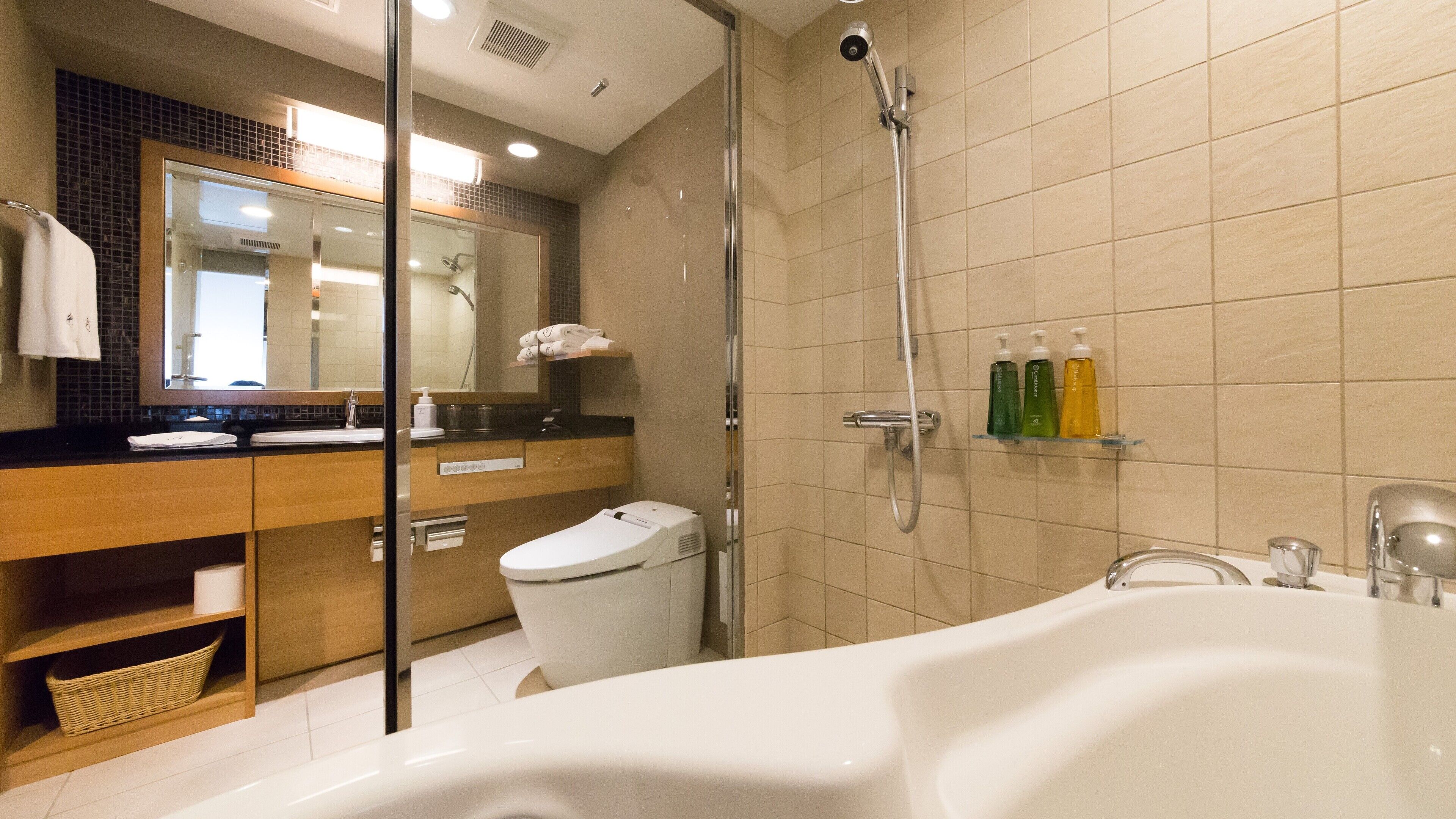 Un baño moderno con bañera, ducha con cerramiento de vidrio, inodoro y tocador con espejo.