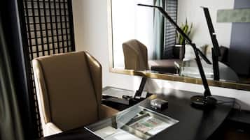 A modern office chair, a desk with a laptop, a lamp, and a glass display case with documents.