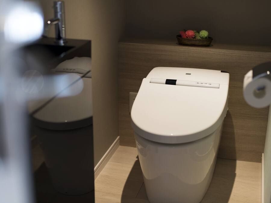 A modern bathroom with a toilet, sink, and a small shelf with decorative items.