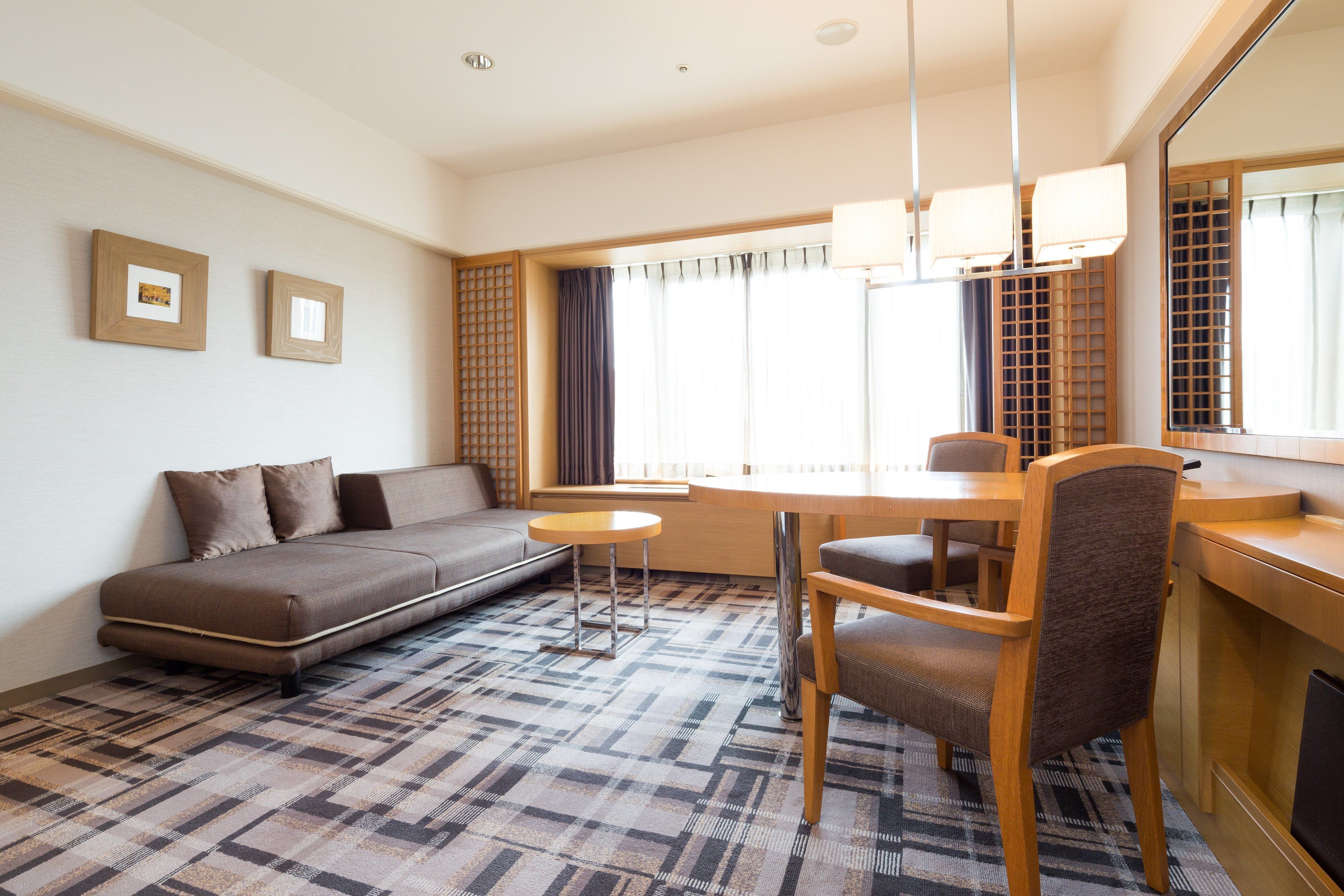 A modern living room with a sofa, dining table, chairs, and a large window with curtains.