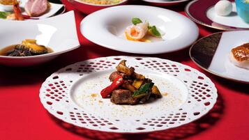 A variety of dishes on a table with a red tablecloth.