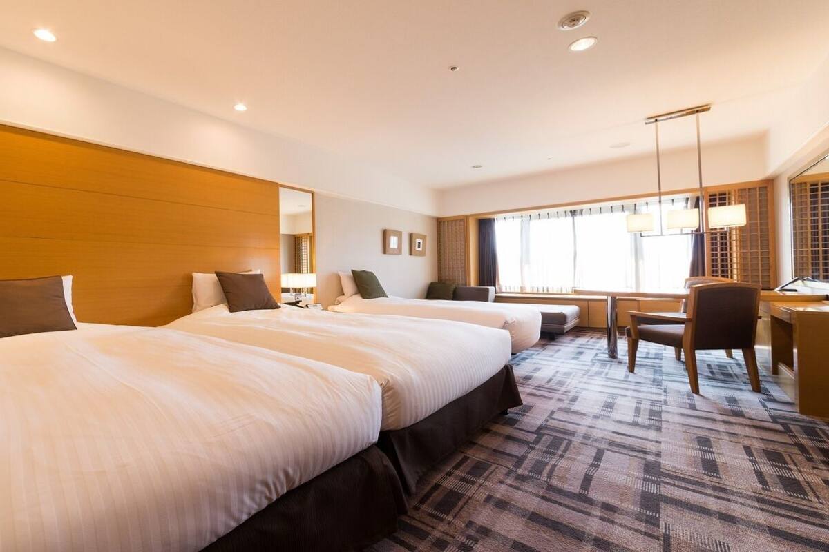 Et hotelværelse med en stor seng, et skrivebord og en stol.