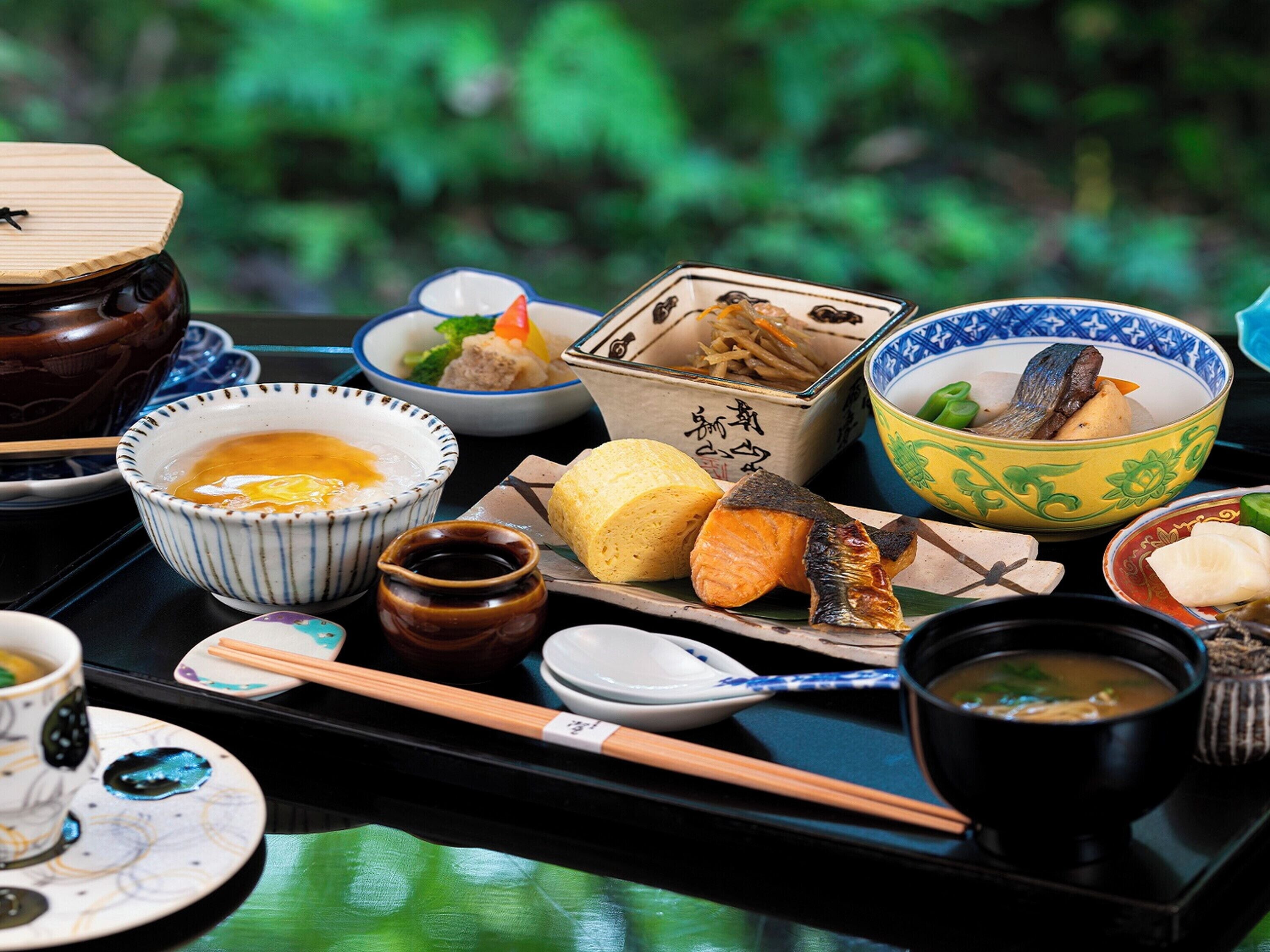 Comida tradicional japonesa con varios platos y utensilios sobre una bandeja.