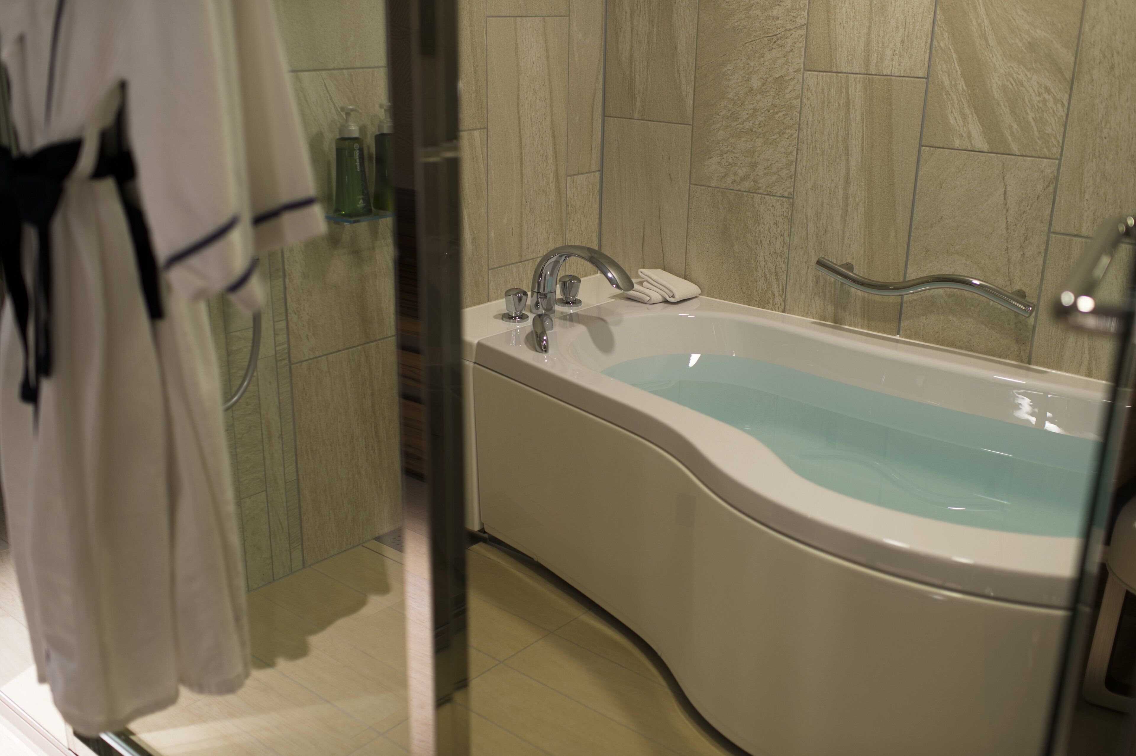 A modern bathroom with a freestanding bathtub, a glass shower enclosure, and a towel rack with robes.