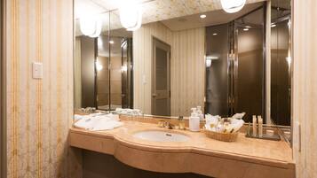 A modern bathroom with a curved sink, a large mirror, and a vanity with toiletries.