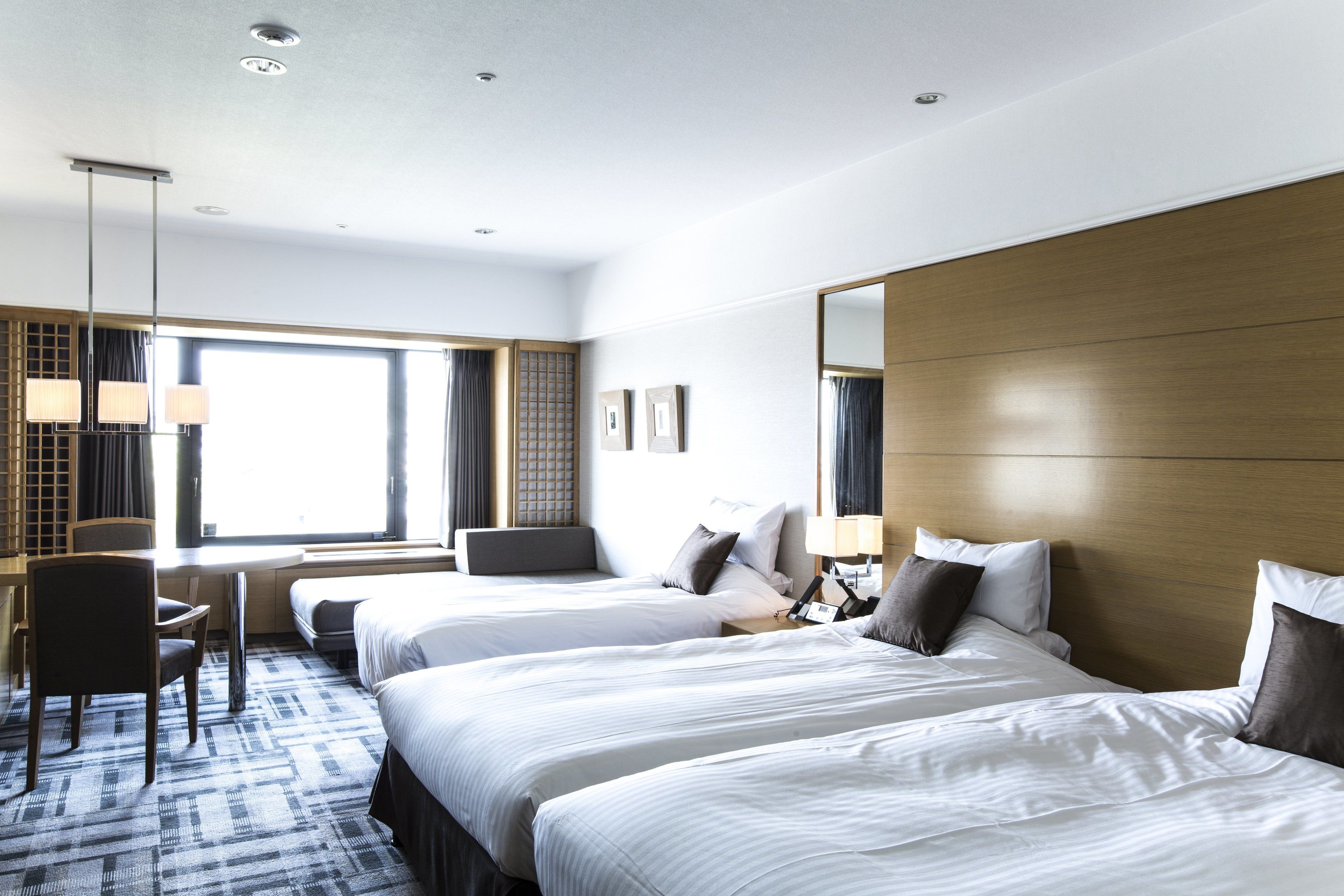 A hotel room with three beds, a desk, and a chair.