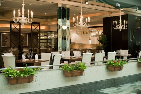 A restaurant with multiple dining tables, chairs, and hanging chandeliers.
