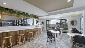 A modern bar area with a counter, stools, and a seating area with tables and chairs. - La Jolla Cove Suites (La Jolla)