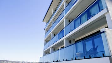 Un edificio de varios pisos con amplios ventanales y balcones, con vistas a la costa.