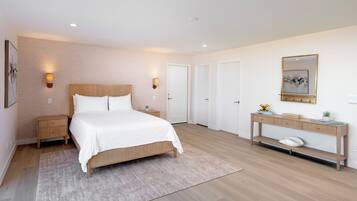 A modern bedroom with a wooden bed, bedside tables, a console table with a mirror, and a small plant.