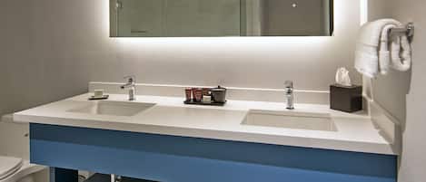 Un baño moderno con dos lavamanos, un espejo grande y un perchero para toallas.