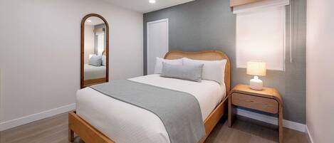 Una camera da letto con un letto, un comodino, una lampada, uno specchio e una finestra.