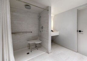 Un baño moderno con cabina de ducha, un taburete pequeño y un lavamanos con espejo.