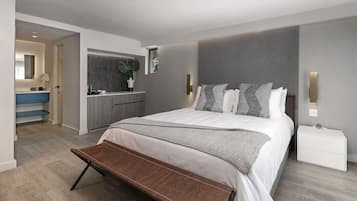 A modern bedroom with a large bed, a bench, a bedside table, and a bathroom visible through an open door.