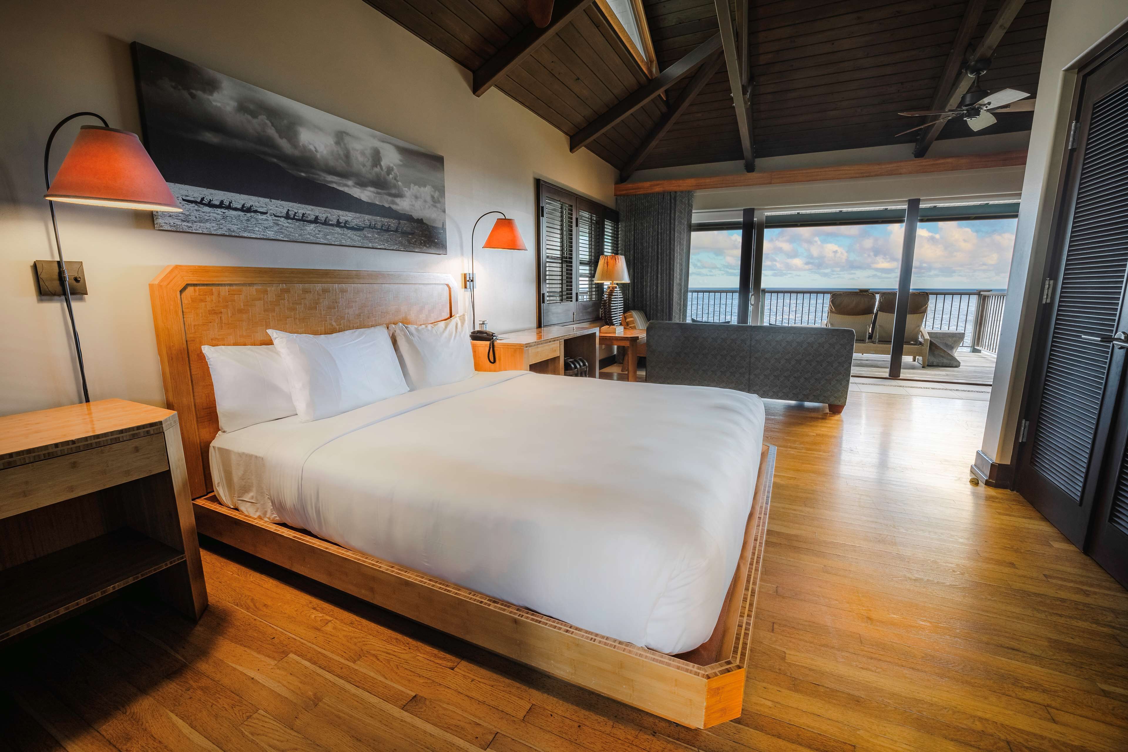 Ein geräumiges Schlafzimmer mit einem großen Bett, einem Holzkopfende und Blick auf den Balkon.