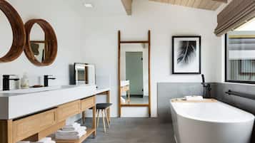 A modern bathroom with a large bathtub, a wooden vanity with a mirror, and a shower area.