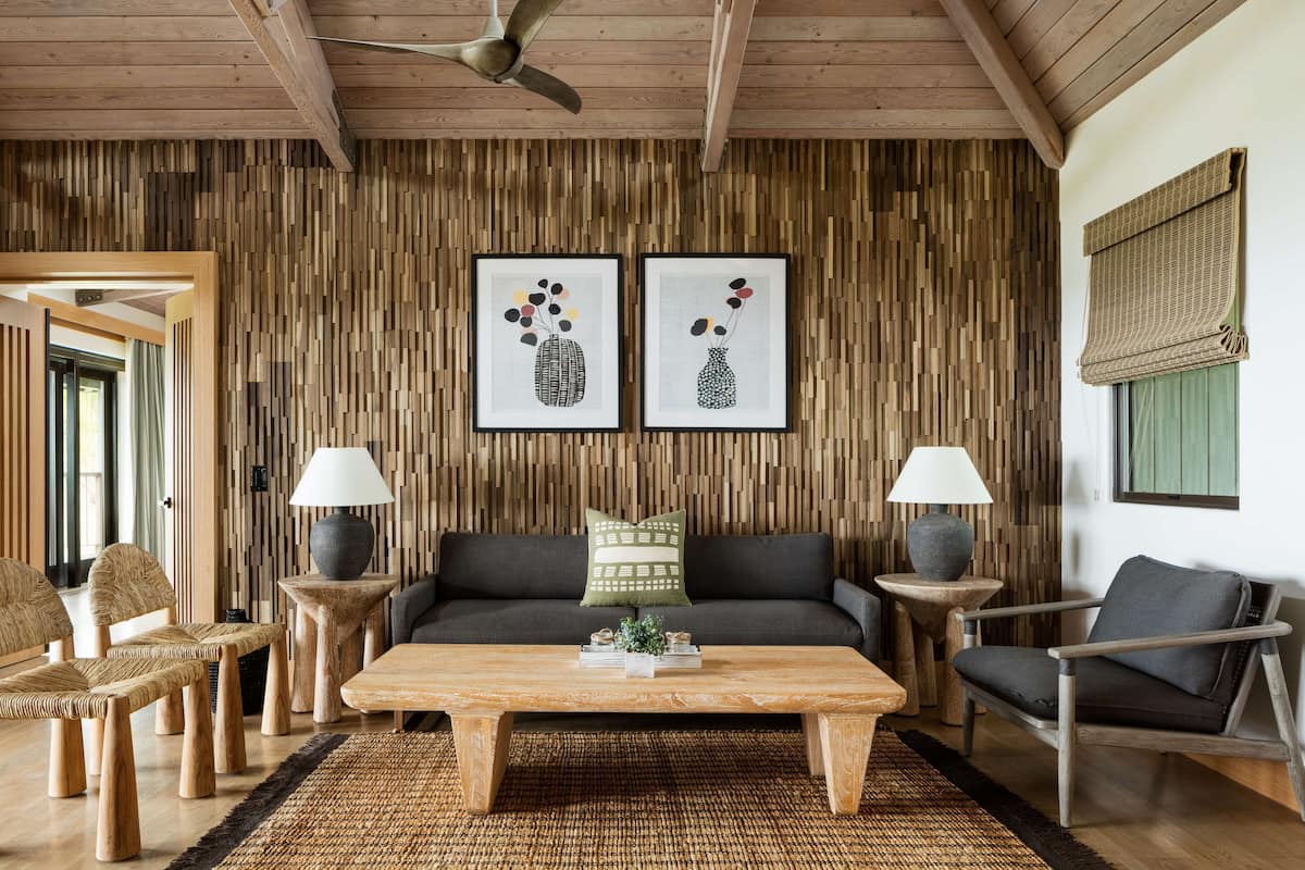 A modern living room with a wooden ceiling, a sofa, two armchairs, a coffee table, and two side tables with lamps.