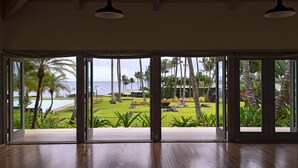 A spacious room with a large sliding glass door leading to a lush garden with palm trees and a view of the ocean. - Hana-Maui Resort, a Destination by Hyatt Residence (Hana)