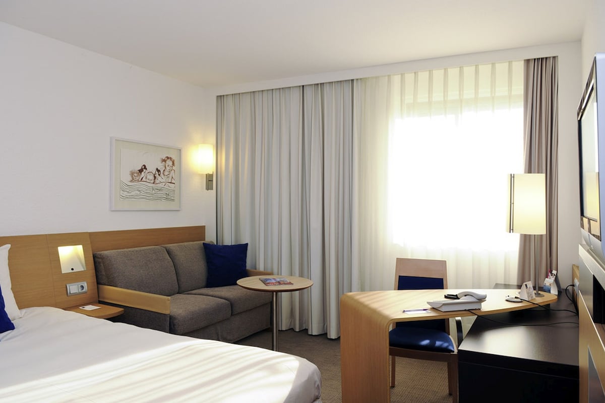 Habitació d'hotel amb llit, sofà, escriptori i televisió.