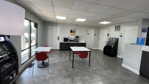 Une pièce propre et moderne, avec deux chaises rouges et une table blanche, un distributeur automatique et une machine à café.