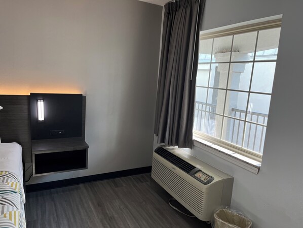 Une chambre d’hôtel équipée d’un lit, d’une télévision, d’une fenêtre avec des rideaux et d’un appareil de climatisation.