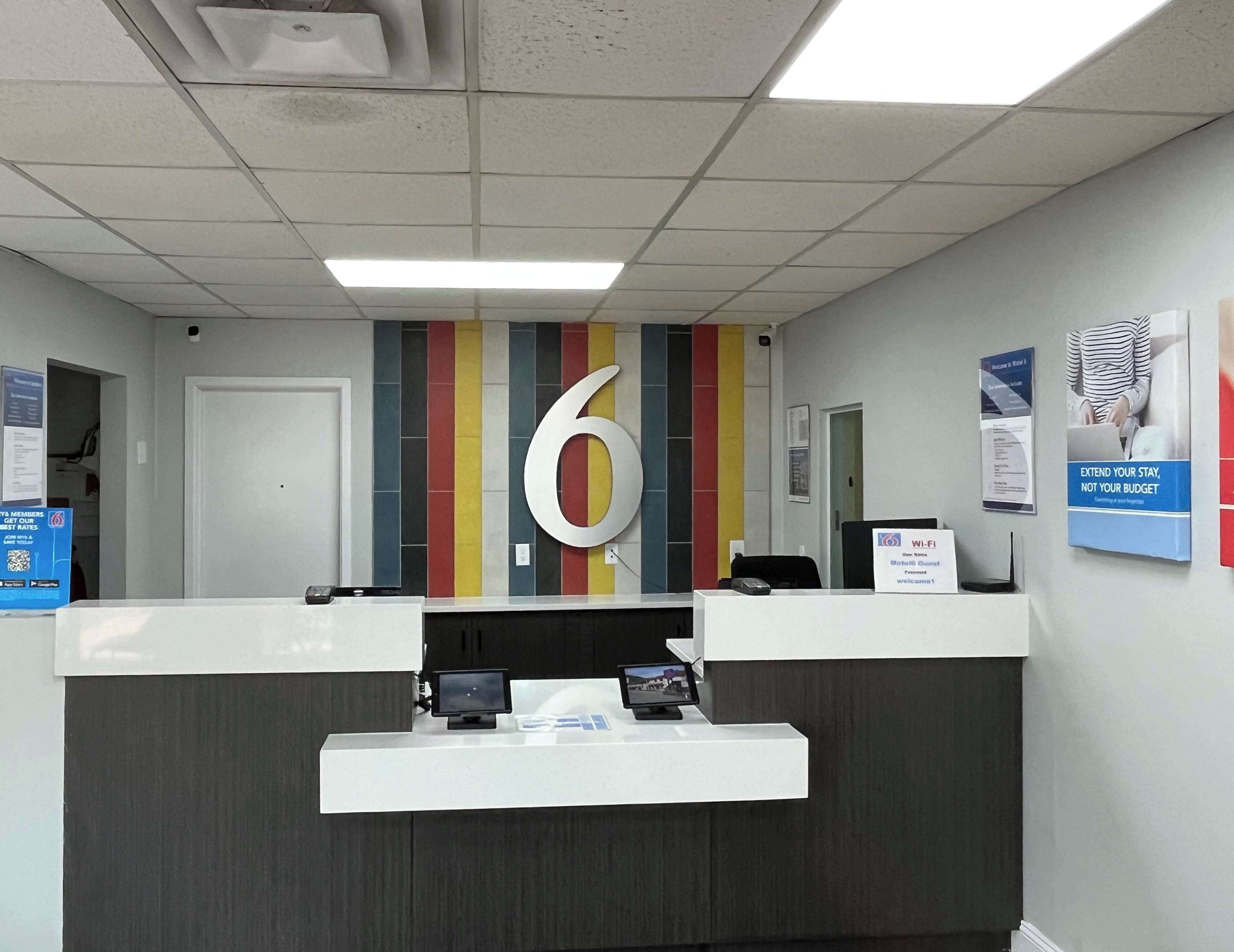 A reception desk with a large number '6' sign, a digital screen, and a sign indicating Wi-Fi availability.