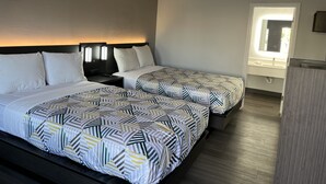 Une chambre d’hôtel avec deux lits, chacun agrémenté de draps à motifs, une table de chevet avec une lampe et une fenêtre donnant sur l’extérieur.