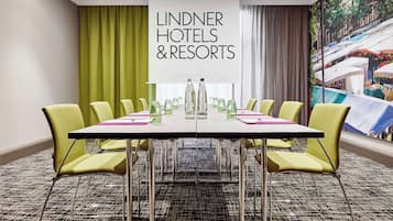 Un salón de conferencias con una mesa, sillas y un cartel que dice "LINDNER HOTELS & RESORTS".